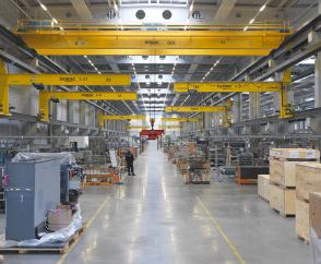 Las grúas puente murales EKWK (con polipastos de cable EKDR de 3,2 t) apoyan el nivel de los puestos de trabajo para el montaje de las máquinas por debajo de las grúas puente de 50 t.