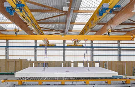 Two Demag V-Girder single girder cranes with synchronized wire rope hoists to transport a large concrete panel