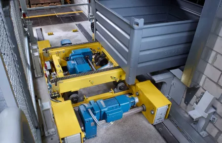 Carriage of an AS/RS system being loaded with a bin. Carriage has Demag AC induction motors and wheel system installed on the yellow carriage.