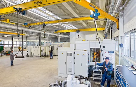 Machinery being served by a wall-mounted I-beam slewing jib and a DCS-Pro chain hoist installed on a U11 manual trolley