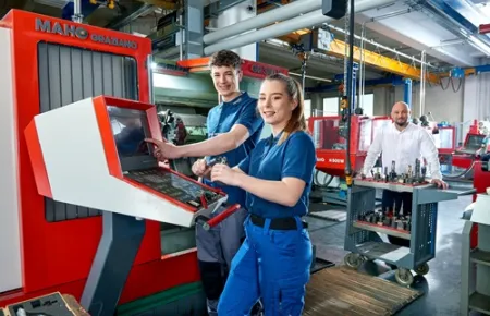 Demag Mitarbeitende in der Lehrwerkstatt an einer CNC-Maschine.