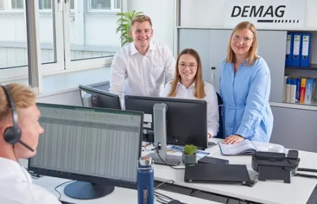 Demag Mitarbeitende im Büro an einem Computer.