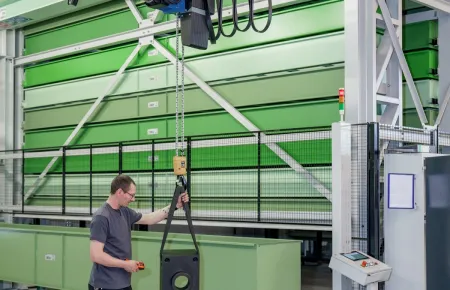 Sytuacja robocza z wciągnikiem łańcuchowym Demag i systemem lekkich suwnic Demag KBK w tle.