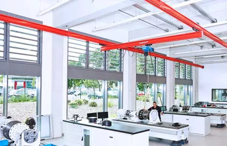 Demag KBK crane and DC chain hoist lifting a component for assembly into a larger unit.