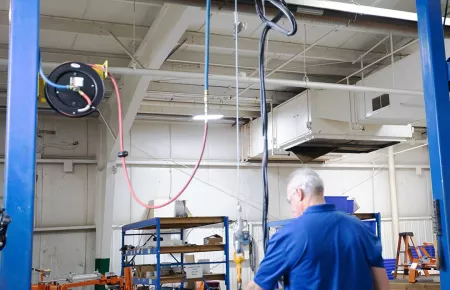 The Demag D-BP II Air Balancer in use with the operator lifting a component.