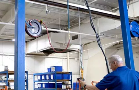 Demag D-BP II Air Balancer used to lift and set a component onto a table for an assembly operation.