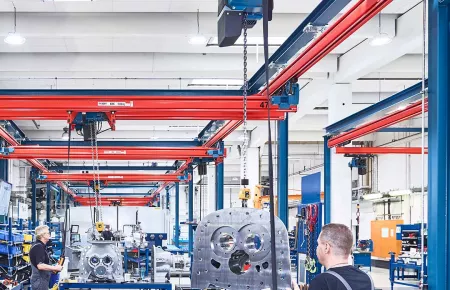 Operator using a DCS Pro chain hoist to lift a component onto a table for assembly.