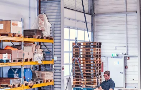 An operator using a Demag DC Com chain hoist to place a component.