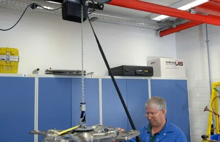 An operator using the DC Com chain hoist to place a component for precise assembly.