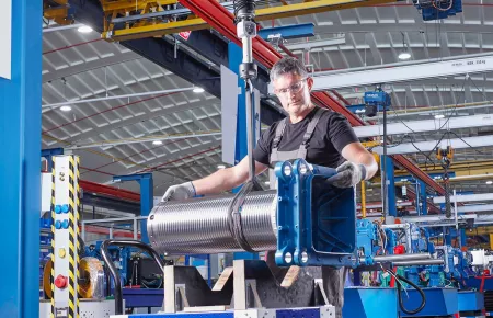 Operator using a DCBS Electric Balancer with both hands on the load to place the component on a rack. 