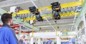 Ein Bedienender steuert einen Kran mit vier Demag Seilzügen DHR per Funksteuerung.